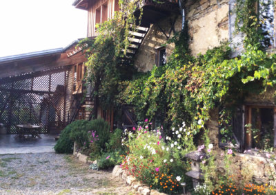 L'extérieur de la maison rénovée écologiquement et recouverte de végétation et de fleurs